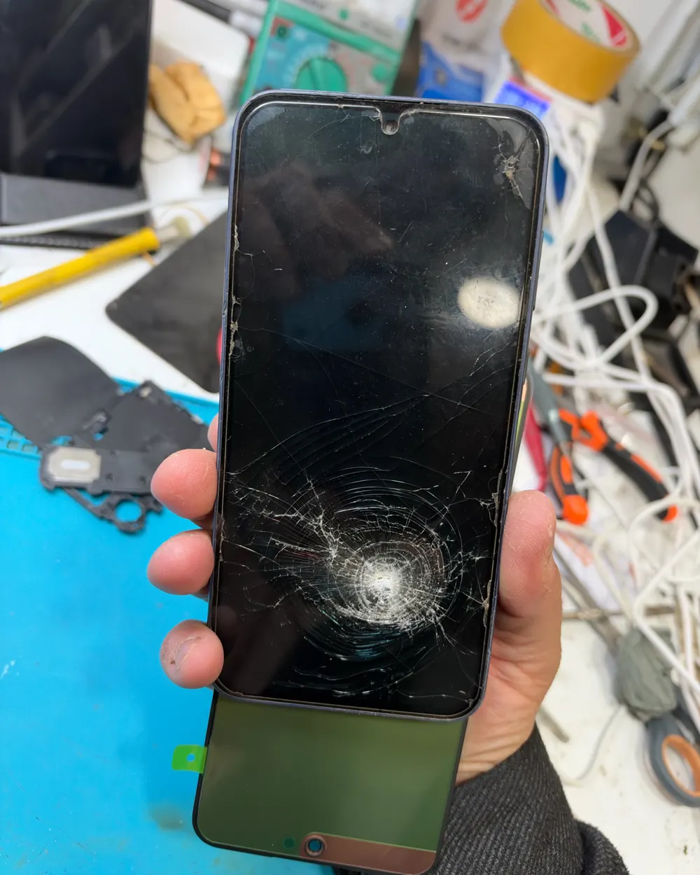 Samsung Galaxy A35 with a cracked screen, held next to a replacement screen panel
